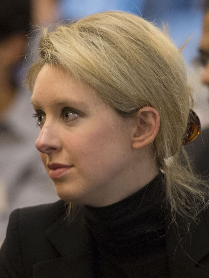 Blonde woman in a black turtleneck and blazer at an event, illustrating famous fraud cases in finance.