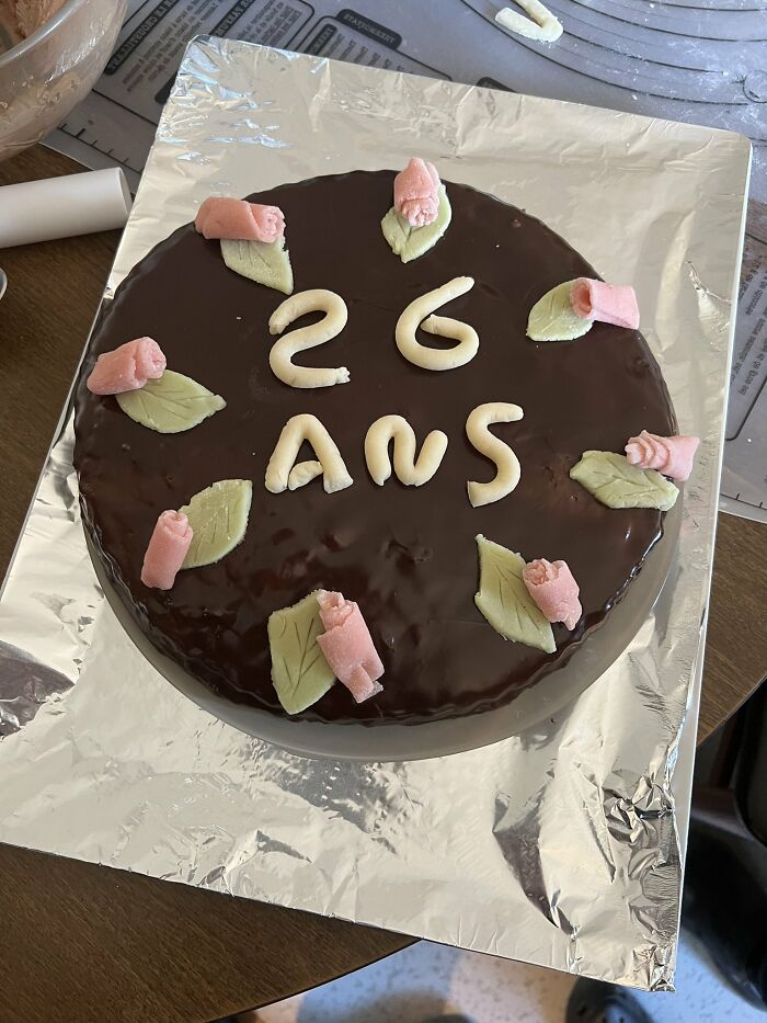 Pastel de chocolate decorado con flores y hojas de fondant, capturando un momento dulce de madres divertidas y familiares.