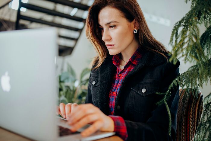 Young woman focused on solving 50-50 questions on a laptop, showcasing sharp thinking skills in a cozy environment.