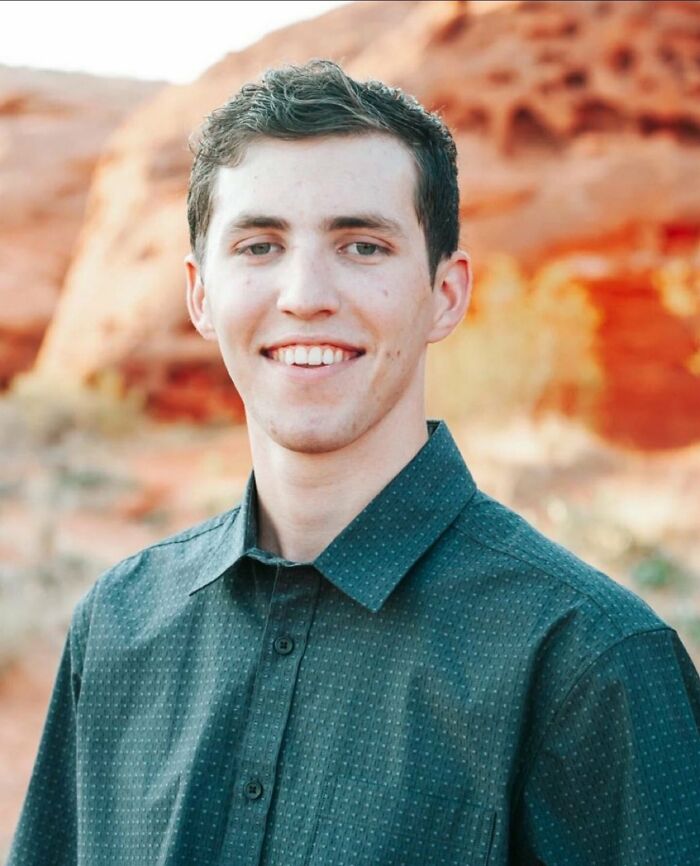 Young man smiling outdoors with red rock formations in the background, related to FBI Director under fire controversy.
