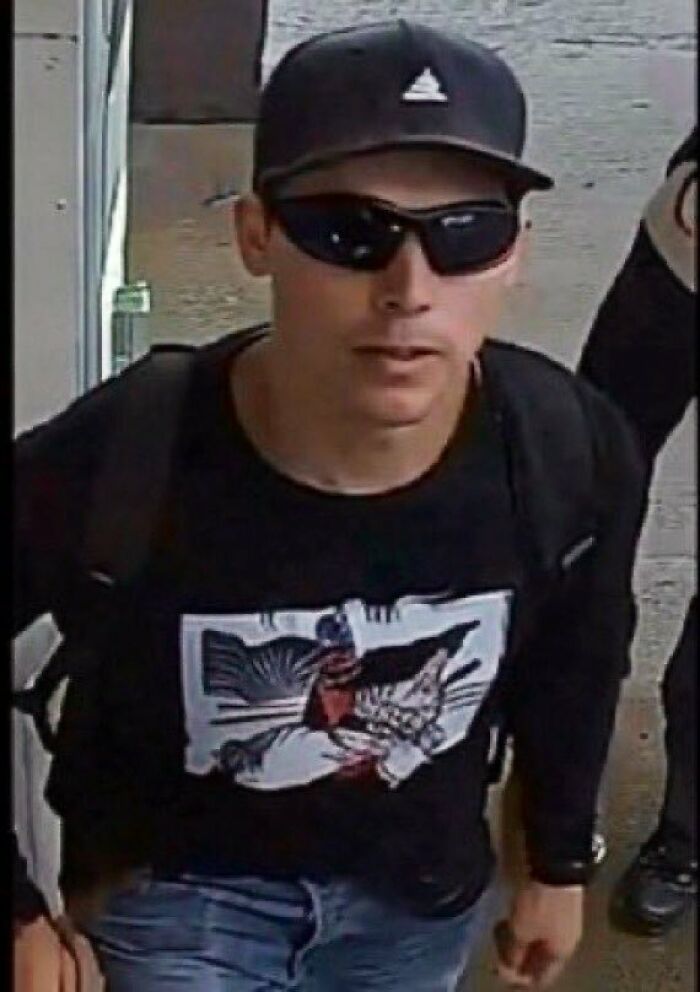 Man wearing black cap and sunglasses with black shirt and backpack in surveillance-style image related to FBI director controversy.