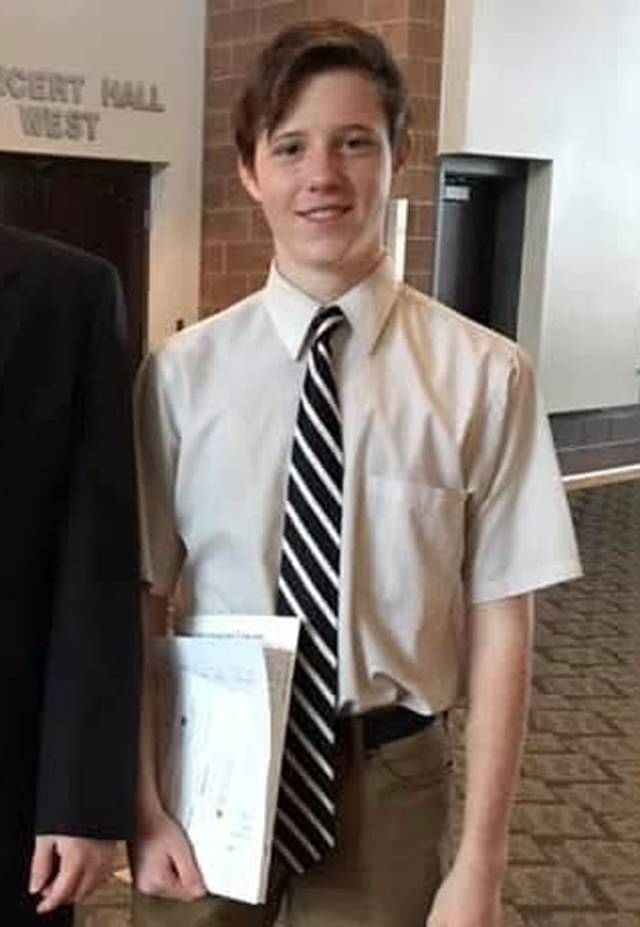 Young man in tie and dress shirt holding papers indoors, related to Charlie Kirk assassin&rsquo;s roommate problematic behavior story.