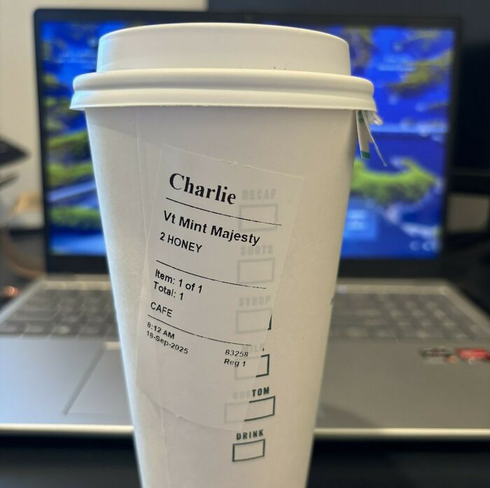 Starbucks cup with Charlie Kirk's favorite drink label, revealing a hidden hate message on the cup in an office setting.