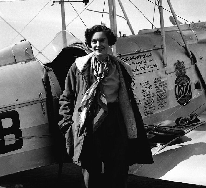 Black and white photo of a woman standing by a vintage plane, related to famous people who lost their lives in animal attacks.