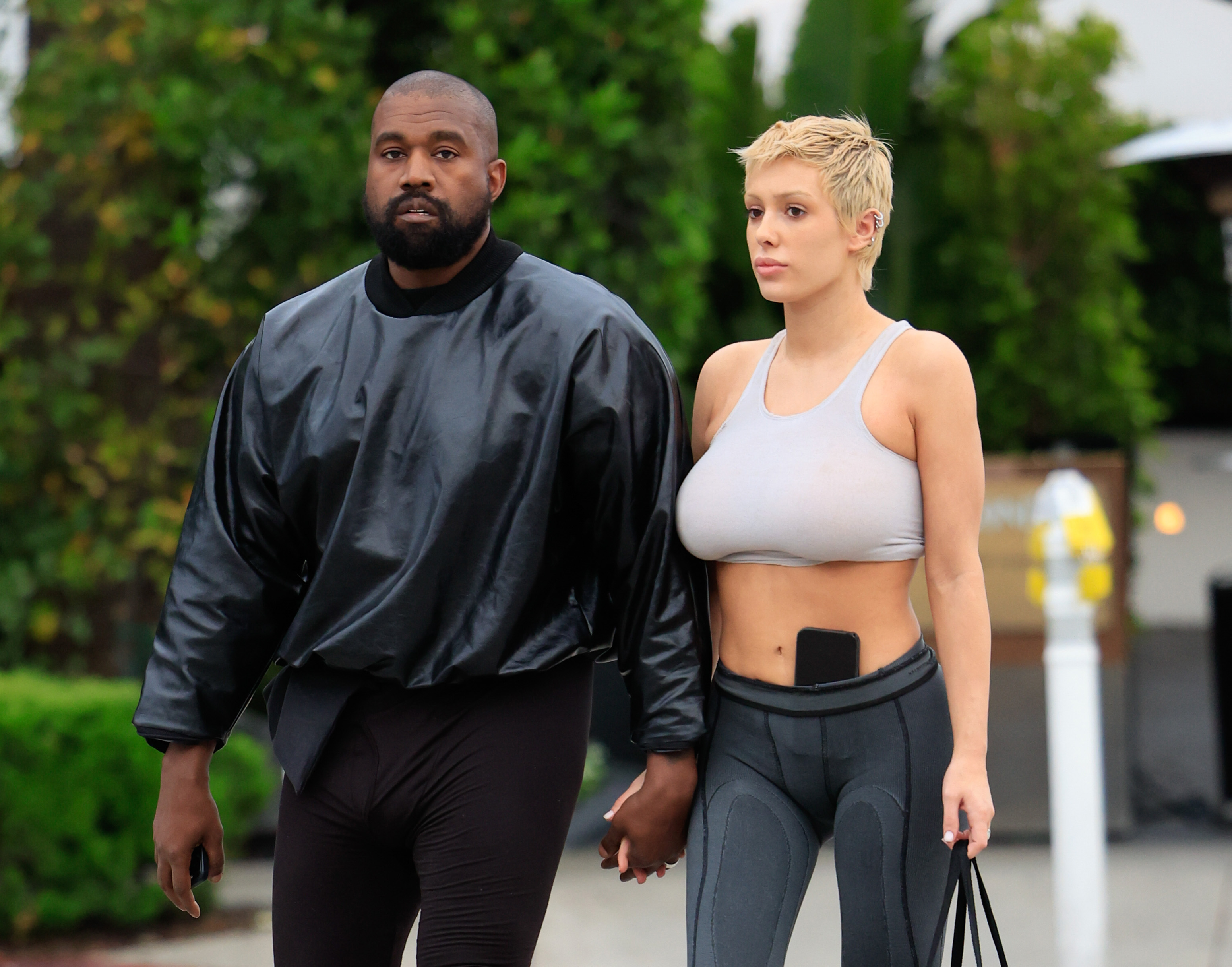 Kanye West and Bianca Censori walking hand in hand, highlighting Bianca Censori&rsquo;s net worth in West&rsquo;s empire.