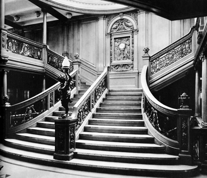 Grand staircase inside the Titanic featuring ornate woodwork and detailed carvings in this rare historical photo.