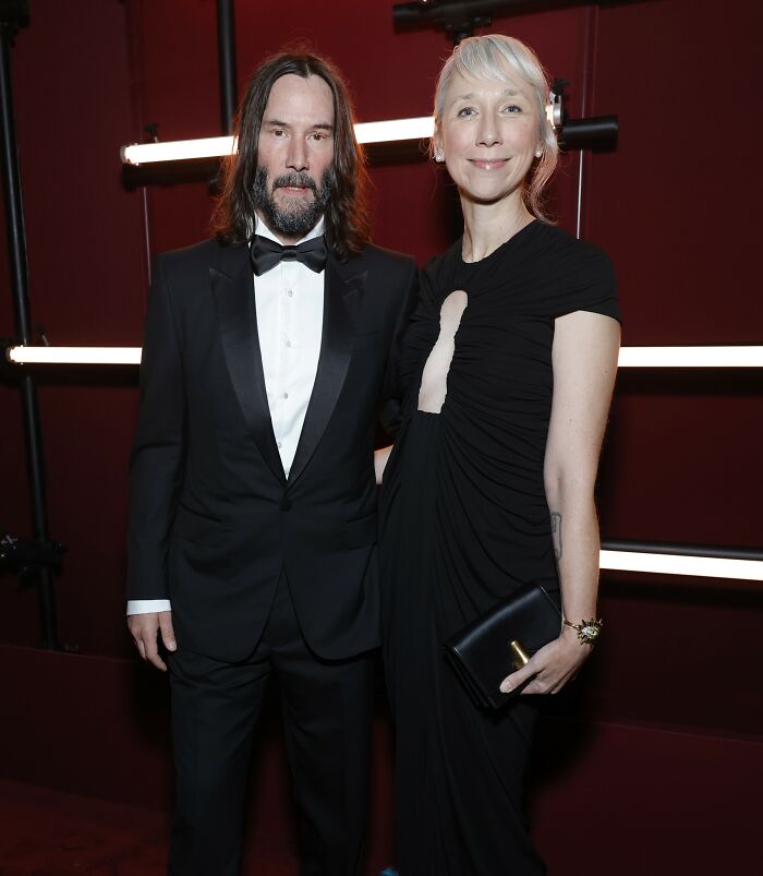 Keanu Reeves and his girlfriend dressed elegantly at an event, addressing marriage rumors in a public setting.