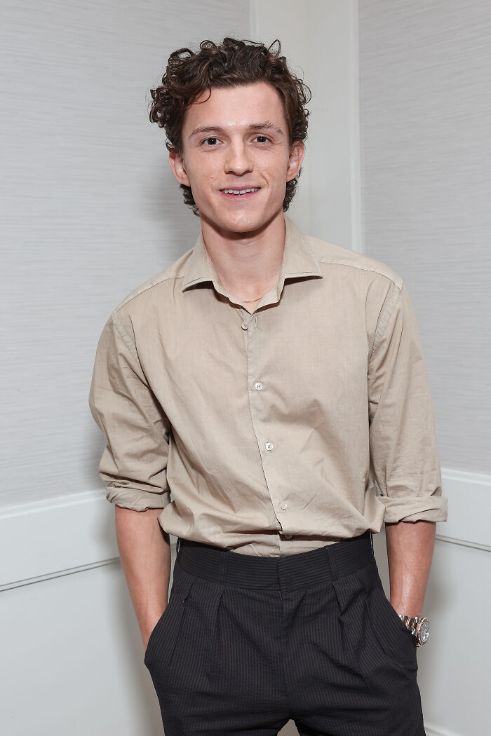 Tom Holland posing indoors wearing a beige shirt and dark pants, linked to Spider-Man stunt head injury news. Tom Holland posing indoors wearing a beige shirt and dark pants, linked to Spider-Man stunt head injury news.