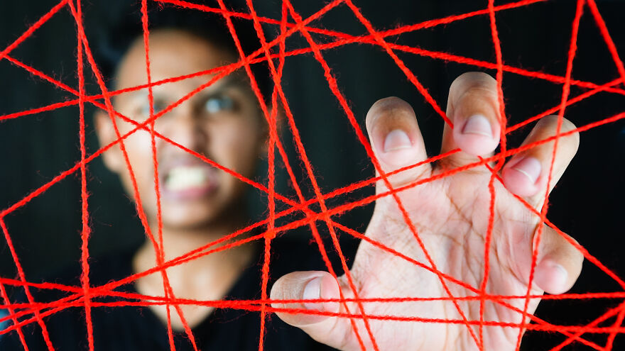 Person interacting with red strings symbolizing invisible string theory in modern romance and the role of destiny.