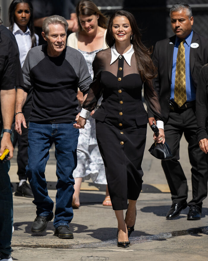 Selena Gomez smiling and walking outdoors with a group, related to mom’s reaction at star-studded wedding to Benny Blanco. Selena Gomez smiling and walking outdoors with a group, related to mom’s reaction at star-studded wedding to Benny Blanco.