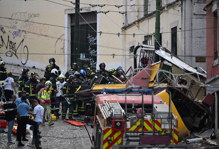 Emergency responders at the scene of an iconic tram crash down a hill, colliding with a building in Portugal.