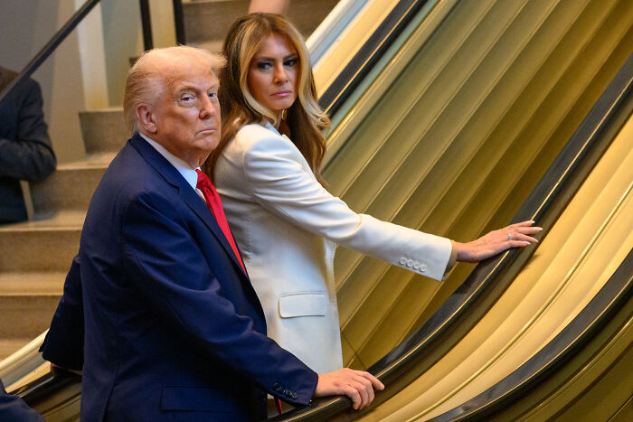Donald Trump and Melania Trump on an escalator with serious expressions, analyzed by body language experts for finger-pointing. Donald Trump and Melania Trump on an escalator with serious expressions, analyzed by body language experts for finger-pointing.