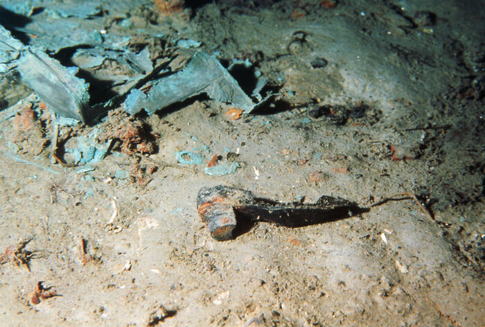 Rusty pipe and debris on the ocean floor near Titanic wreckage captured in rare historical maritime photo.