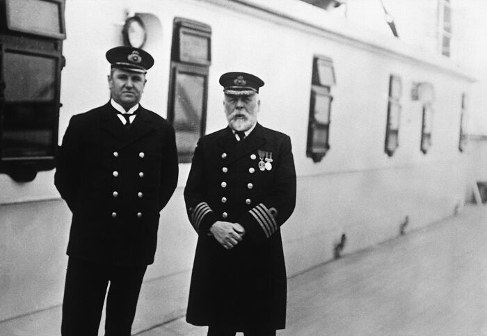 Two Titanic officers in uniform standing on the ship's deck in a rare historical photo of the Titanic.