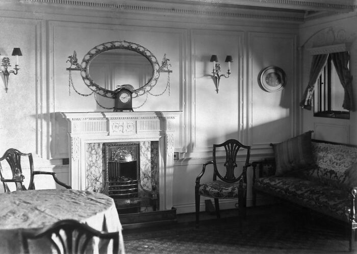 Rare historical photo showing the elegant interior lounge with fireplace and vintage furniture on the Titanic ship.