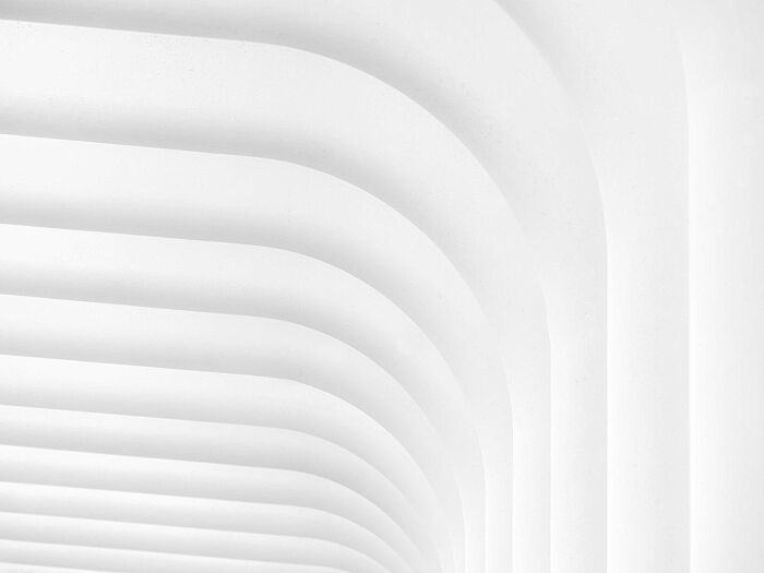 Curved white architectural structure with clean lines and soft shadows showcasing minimalism and stunning simplicity.