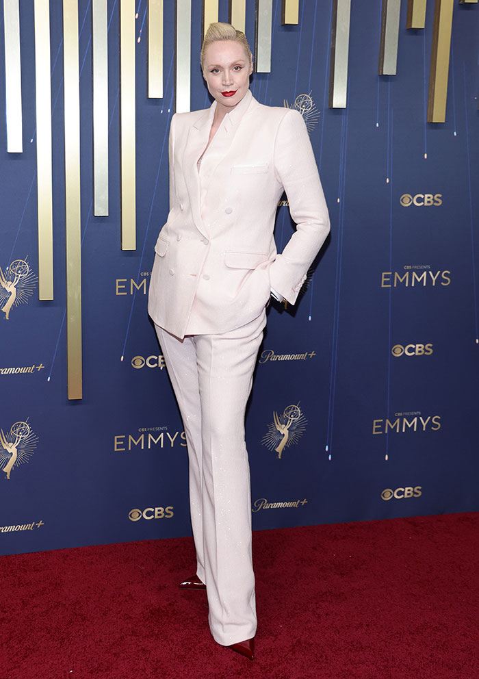Persona con traje blanco posando en alfombra roja de los Emmys 2025, destacando en mejores y desastres de moda.