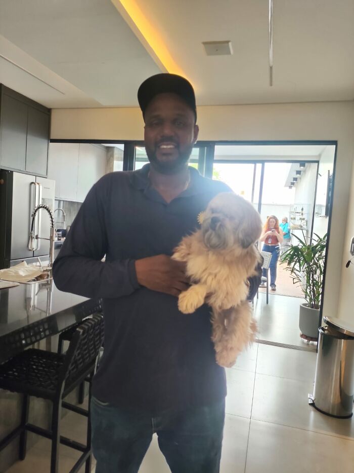 Pool attendant holding a blind dog indoors, highlighting a heart-stopping rescue from drowning. Pool attendant holding a blind dog indoors, highlighting a heart-stopping rescue from drowning.
