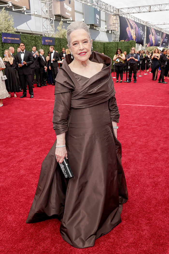 Mujer elegante en vestido marrón largo en la alfombra roja, destacando como mejor vestida en los Emmys 2025.