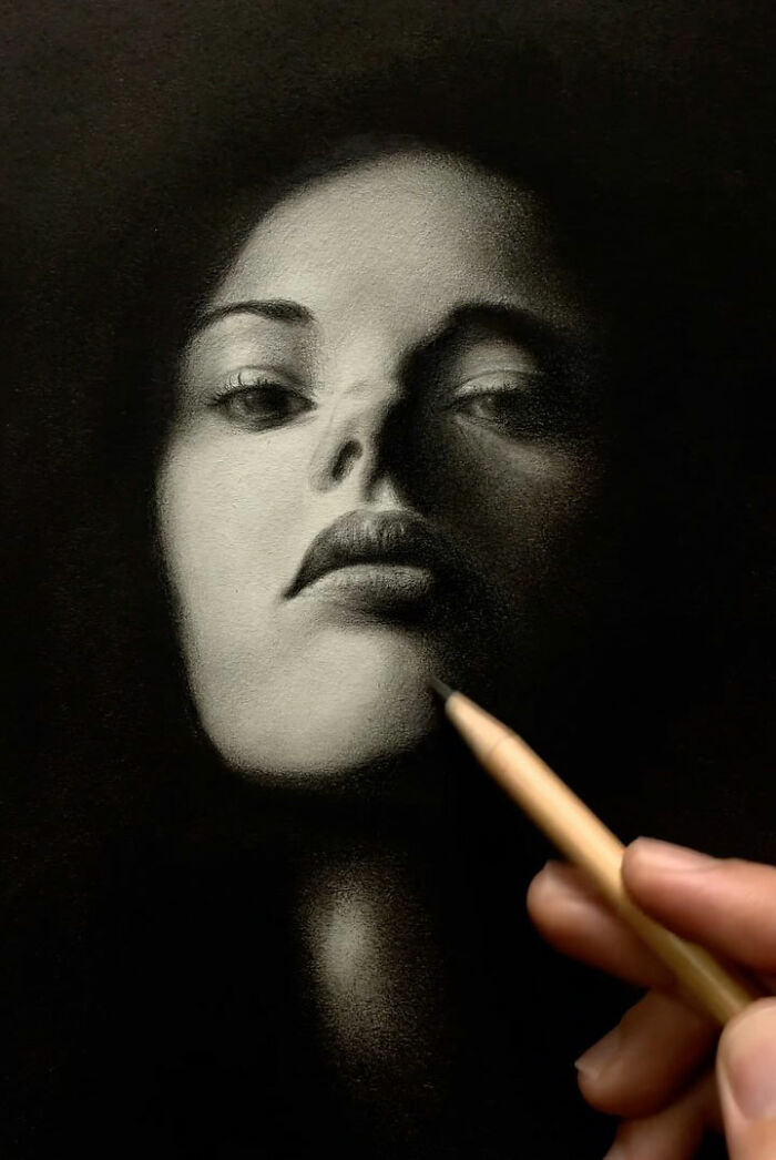 Hand drawing a realistic pencil portrait of a woman with detailed shading capturing every tiny facial feature.