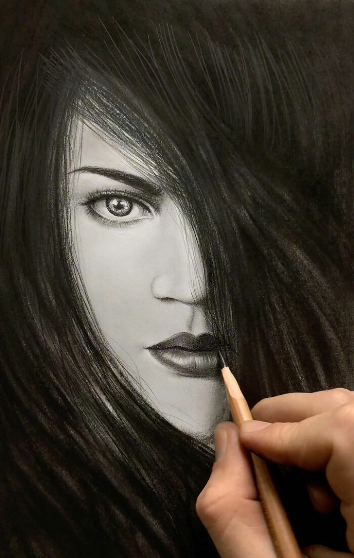 Hand drawing a pencil portrait of a woman's face with intricate details capturing every tiny feature.