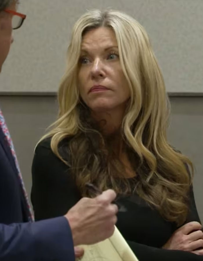 Woman with long blonde hair and black top listens intently during a conversation about convicted doomsday cult mom.