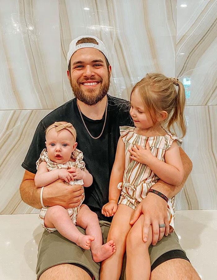 Man sitting with two young children, representing surviving son in story about doomsday cult mom at CrimeCon.