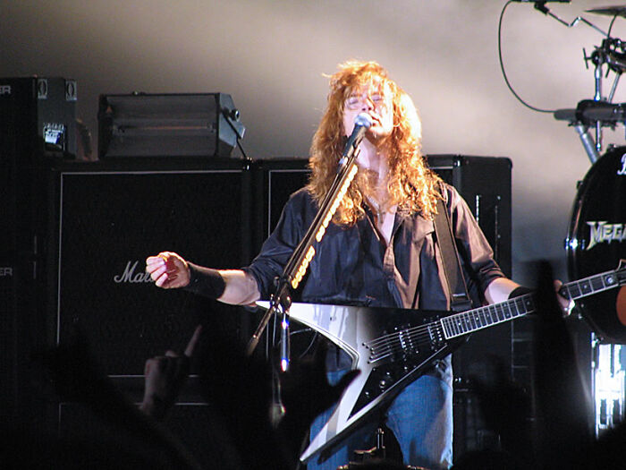 Rock musician performing with electric guitar on stage, representing bold decisions with massive impact on the world.