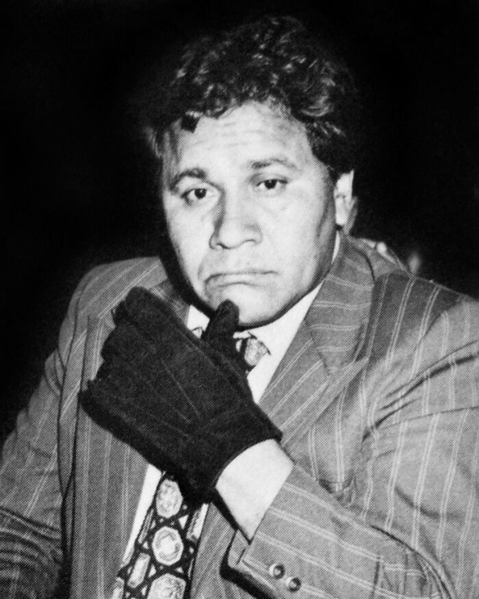 Black and white photo of a man in a suit and patterned tie wearing a glove, linked to celebrities who vanished without a trace.