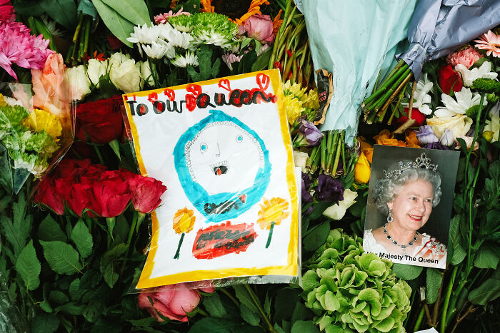 Flowers and a child's drawing laid in London capturing the atmosphere after the Queen’s passing.