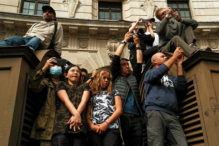 Crowd in London capturing the atmosphere with cameras and phones after the Queen’s passing during a public gathering.