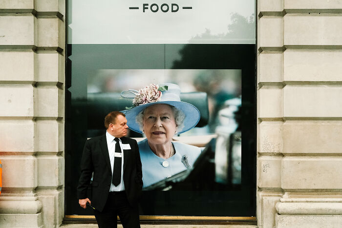 Photographer captured London atmosphere showing a security guard in front of a large portrait of the Queen after her passing.