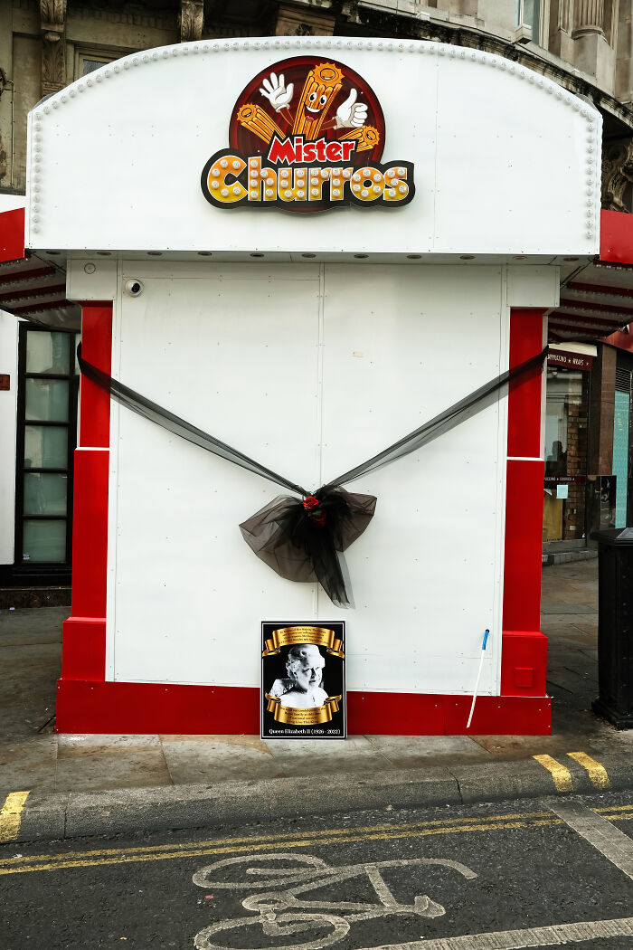 Closed Mister Churros stand decorated with black ribbon and a tribute to Queen Elizabeth in London after her passing.