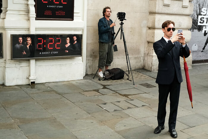 Photographer capturing the atmosphere in London street after the Queen’s passing, with a man in a suit holding a phone.