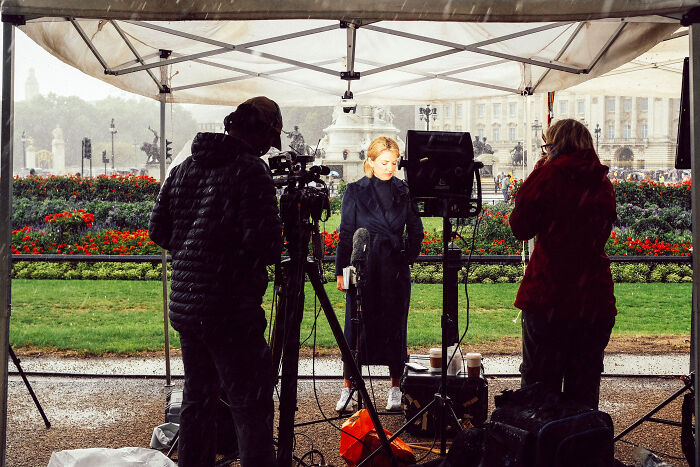 Reporter filming under a tent in London, capturing the atmosphere after the Queen’s passing near Buckingham Palace.