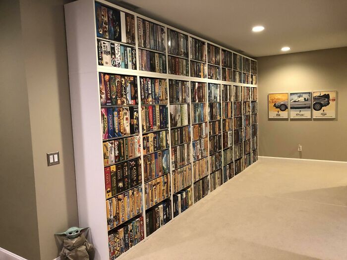 Wall-sized board game collection in a spacious room, highlighting an eye-catching display for travel and leisure enthusiasts.