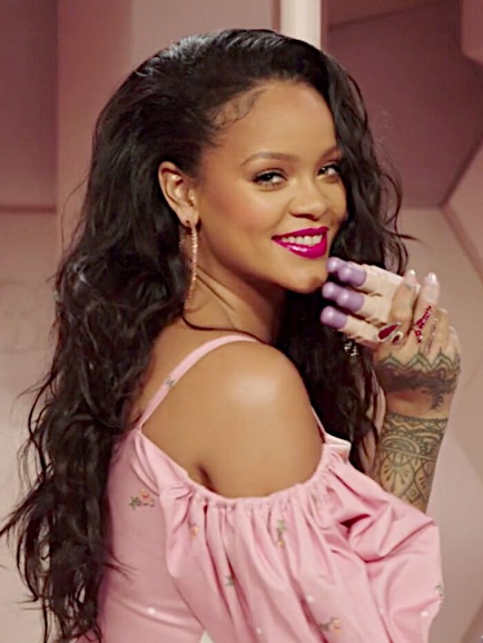 Rihanna smiling in a pink off-shoulder dress showcasing tattoos, highlighting celebrity encounters with worst experiences.