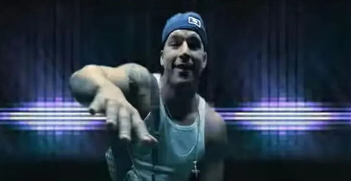 Man wearing a backward cap and tank top, in a dark room with neon lights, related to celebrities who vanished mystery.
