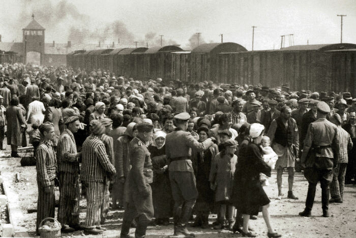 Black and white photo of prisoners in striped uniforms at a train station, depicting a bizarre real life moment.