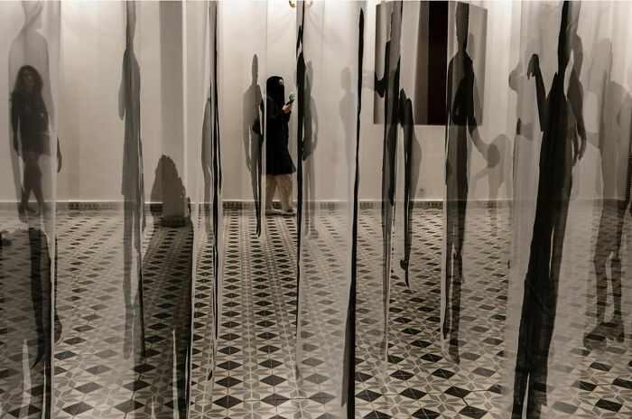 Woman seen through distorted glass panels creating abstract shadows in entertaining street photographs showcasing perfect timing.