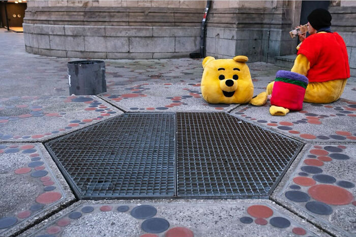 Street photograph of a person in a costume beside a removed character head, showcasing perfect timing in street photography.