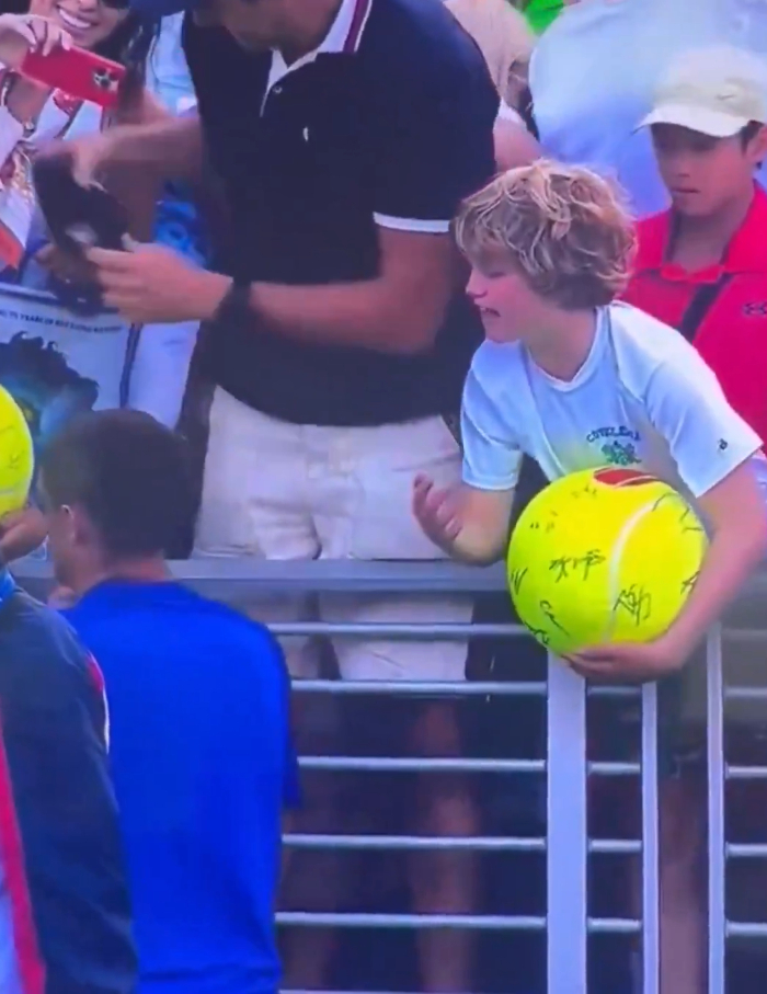 Young boy at US Open holding oversized signed tennis ball while bystanders watch as disgraced CEO snatches cap in viral video. Young boy at US Open holding oversized signed tennis ball while bystanders watch as disgraced CEO snatches cap in viral video.