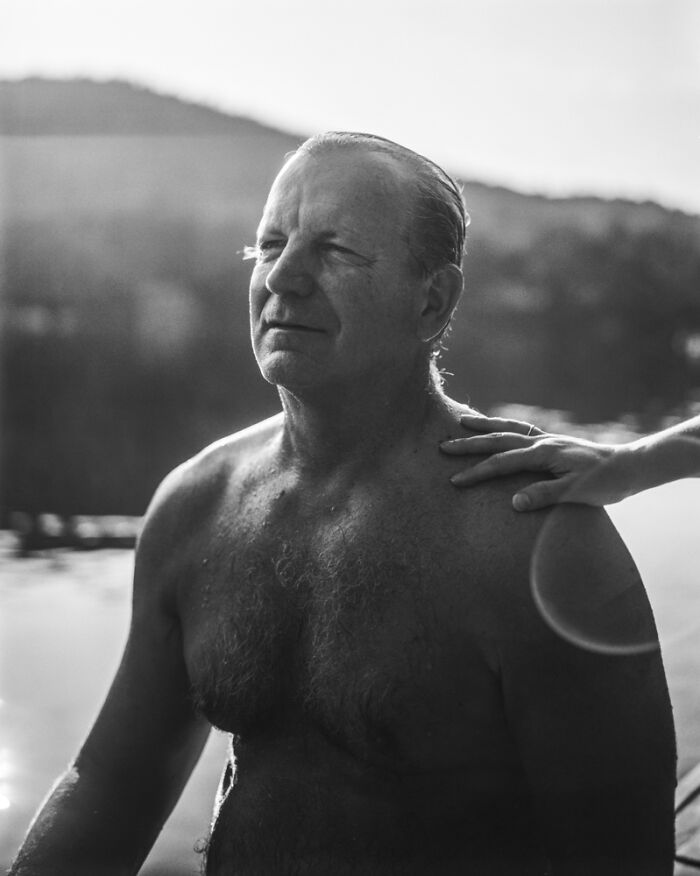 Black and white analog photo of a man by water with a hand on his shoulder, showcasing film photography art.