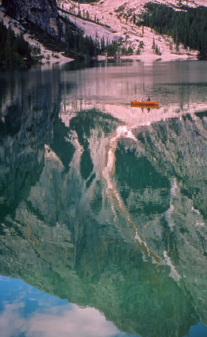 Two people in a canoe on a lake with mountain reflections, a striking analog photo from the 2025 Analog Sparks Awards.