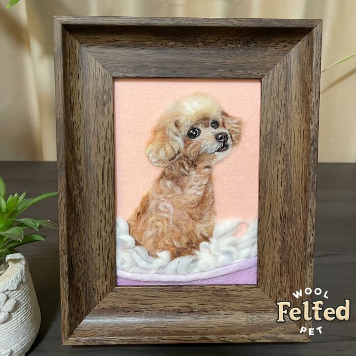 Framed wool felt pet sculpture of a small dog with realistic fur texture and expressive eyes on a soft background.