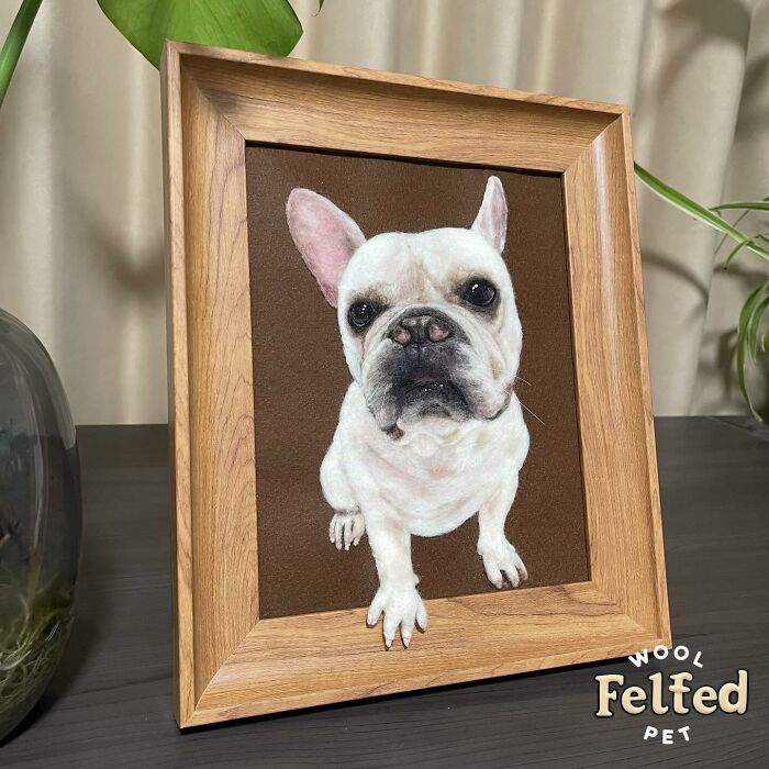 Realistic wool felt pet portrait of a white dog with large ears in a wooden frame, showcasing detailed needle felting art.