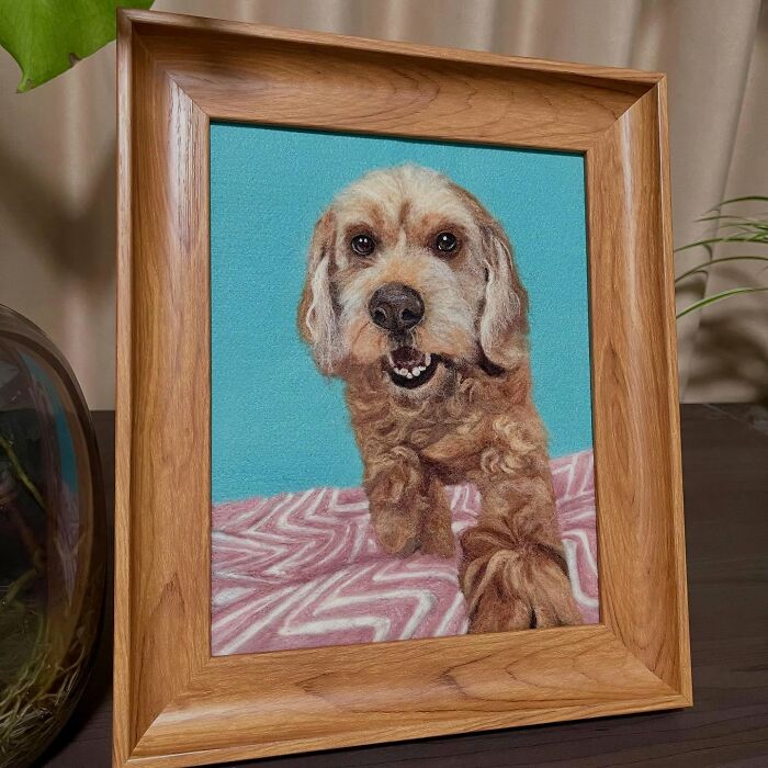 Framed wool felt pet artwork of a realistic dog on a patterned blanket with a blue background.