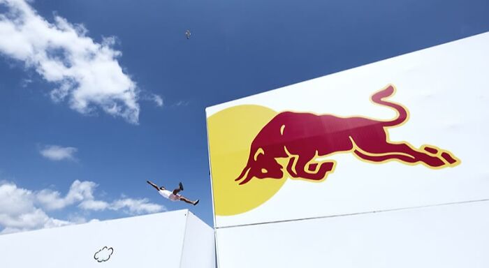 Person mid-air jumping between white buildings under blue sky, a stunning photo showcasing action and architecture.
