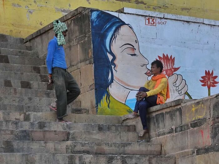 Two people on stone steps near a wall with colorful mural, featured on Instagram page collecting stunning photos worldwide.