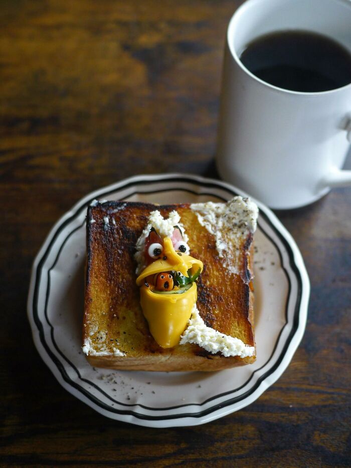 Creative meal by a Japanese mom featuring toast decorated with cheese and vegetables, served with a cup of black coffee.